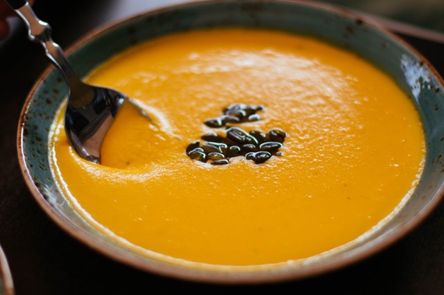 Bowl of butternut squash soup with a handful of black beans floating on top