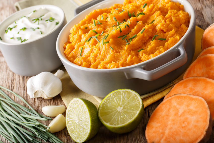 Spicy mashed sweet potato with onion, garlic and lime close-up in a saucepan on a table. horizontal