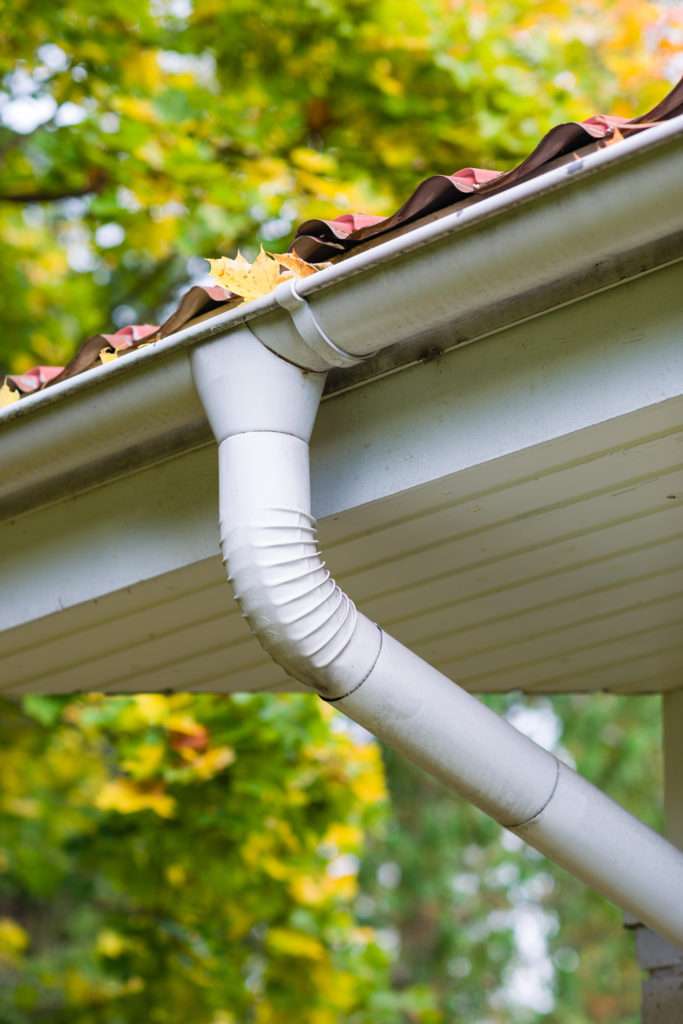 closeup of a gutter on a roof and the downspout below it. Part of a system to save rainwater